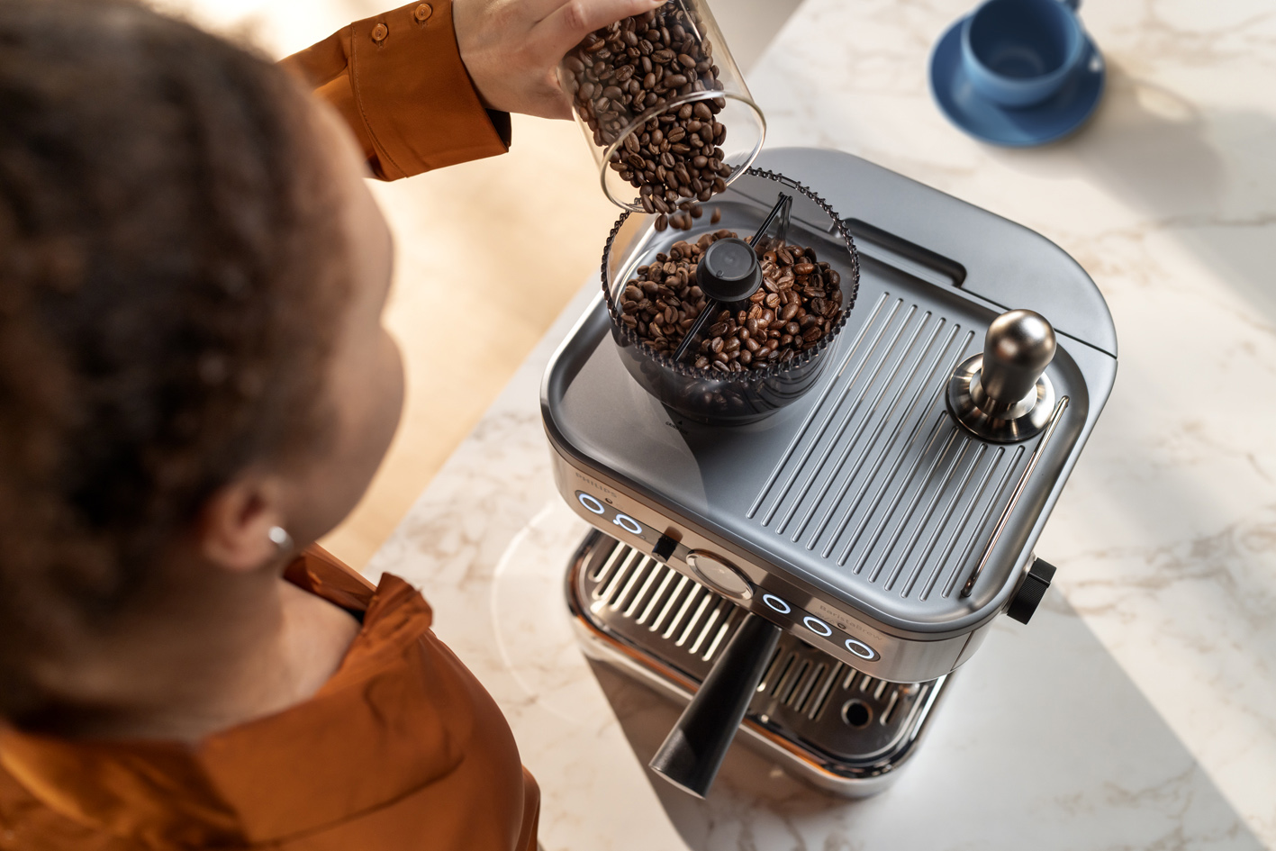 Млада дама изсипва кафени зърна в контейнера за кафе на зърна за Philips Barista Brew